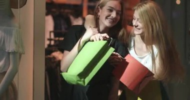 Alışveriş gezisinden sonra alışveriş merkezinin girişinde durup alışverişlerini tartışan iki çekici bayan müşteri. 4K video