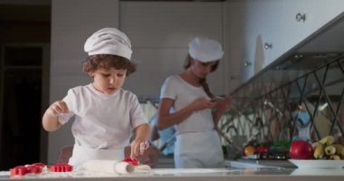 Mangırı küfle kesen küçük çocuğun portresi. Genç anne mutfakta oğluyla yemek pişiriyor, kirli elleriyle, hamur işi yapıyor. 4K video