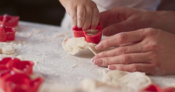 Retrato de niños pequeños y sus madres manos ordenadas que corta la masa con moho. Madre joven está cocinando en la cocina con su hijo, manos sucias, hacer la masa para hornear. Vídeo 4K — Vídeo de stock