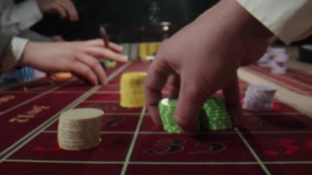 轮盘赌桌上，有人手把筹码放在赌场里。不知名的人坐在赌场的轮盘赌桌后，一边喝威士忌，一边抽雪茄，一边下注。轮盘轮盘 — 图库视频影像