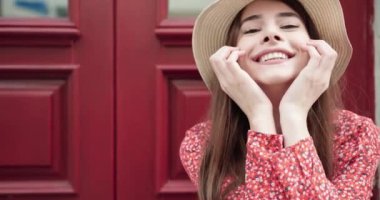 Beyaz arka plan aleyhine poz uzun saçlı ve şapkalı gülümseyen sevimli bir kızın portresini kapatın.