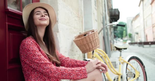 Slank jong brunette meisje poseren met een vintage fiets op een achtergrond van het gebouw — Stockvideo