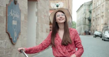 Uzun siyah saçlı çekici bir kız sokakta bir bisiklet taşıyor. Esmer, gözlüklü, bisikletli, şehir caddesinde