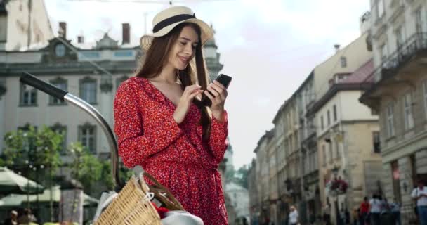 Bright Street portret aantrekkelijke vrouw in een pak staan op straat en kijken naar het scherm van een smartphone op een stad achtergrond — Stockvideo