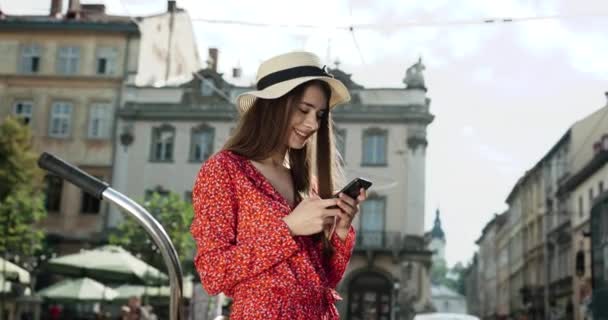 A nő okostelefont használ az európai városban. Csípő lány böngészés Internet a telefon, textil-és kommunikáció a szabadban. Utazási koncepció. — Stock videók