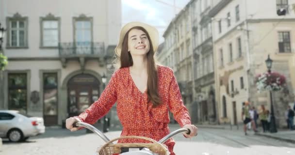 자전거에 모자에 매력적인 젊은 갈색 머리의 야외 패션 초상화 — 비디오