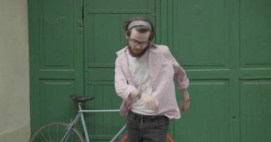 4 bin. Ağır çekim. Yeşil kapının önünde gözlüklü yakışıklı sakallı adam dans ediyor. Hippi alt kültürü