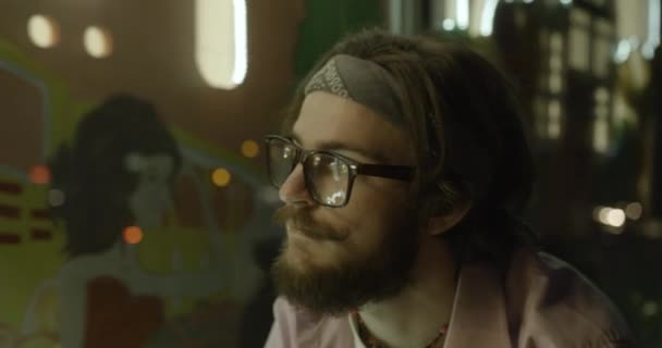 4 bin. Kasabadaki hippi erkek turist. Gözlüklü sakallı adam parlak vitrinler boyunca bisiklet sürüyor.. — Stok video