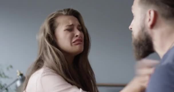 Молодая пара, у которой проблемы с пьяным мужем или мужчиной, нападающими и угрожающими жене или девушке, плачущей на полу испуганной и напуганной домашним насилием — стоковое видео