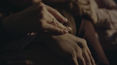 Manikürlü bir kadın eli bir erkeğin elini nazikçe okşar. Alyansları olan bir erkek ve bir kadının elleri. Birbirine aşık çift.