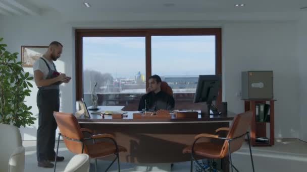 Бизнесмен сидит в офисном кресле, в то время как грузчики обвиняют конфискованное имущество. Ускоренные съёмки. — стоковое видео