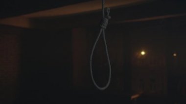Düğümlü halatın yakın çekim görüntüsü ve karanlık odada döngü. Cellat düğümlü halat sallanıyor.