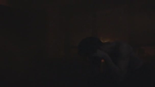 In een donkere kamer zit een depressieve man die zelfmoord wil plegen door op te hangen. Ging voor opknoping in een donkere kamer. — Stockvideo