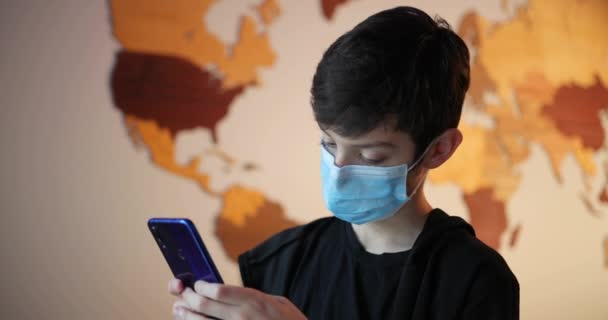 스마트폰을 들고 의료용 마스크를 쓴 소년, 자립심 과 격리, 사람들 — 비디오