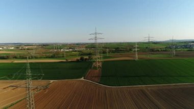 Elektrik, boş yeşil ve sarı alanların arasında gökyüzüne karşı destek veriyor. Medeniyet arka planda görülebilir, arabalar asfalt yolda gidiyor. Güneşli bir gün, yaz, kırsal, yüksek