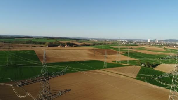 Elektriska stöd mot himlen bland tomma gröna och gula fält. Civilisationen syns på bakgrunden. Solig dag, sommar, landsbygd, högspänningsledning. 4K-video. — Stockvideo