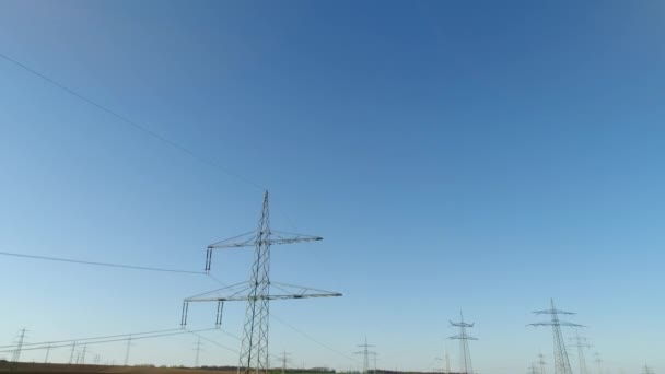 空の緑と黄色のフィールドの間で空に対する電気のサポート。晴れた日、夏、田舎、高電圧線。4Kビデオ. — ストック動画