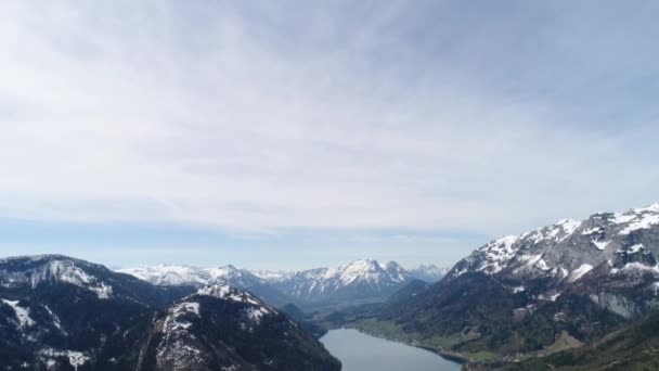 Paisagem aérea do belo Lago Grundlsee no meio dos Alpes austríacos na primavera. Paisagem da aldeia austríaca, montanhas facilmente cobertas de neve e belo lago azul entre eles. 4K — Vídeo de Stock