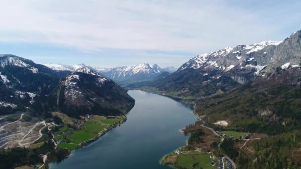 Flyglandskap vid den vackra Grundlsee-sjön mitt i de österrikiska alperna på våren. Landskap av austriska byn, lätt snötäckta berg och vacker blå sjö bland dem. 4K — Stockvideo