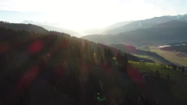 Montañas alpinas al atardecer. Drone vista de la aldea austriaca y picos nevados de los Alpes en la primavera. Bosque verde, campo, cielo blanco y día soleado. Europa. Vídeo 4K. — Vídeos de Stock