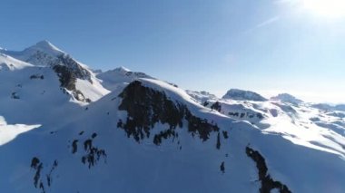Avustralya Alpleri 'nin karlı tepelerinde hava aracı görüntüsü. High Mountain Range 'den panoramik manzara. Mavi gökyüzü güneşli. Avrupa. Kış. 4K video.