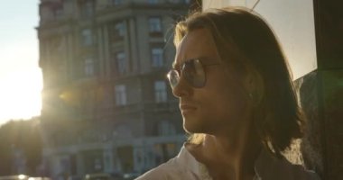 Gün batımında arka planda ve gökdelenlerde duran gözlüklü çekici genç adamın portresi..