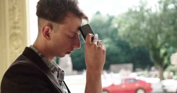 Homem preocupado infeliz sentado com smartphone na mão. um jovem está esperando por uma chamada importante. — Vídeo de Stock