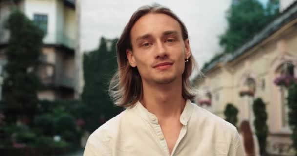 Joven hombre guapo caminando mirando hacia los lados endereza su cabello y sonriendo — Vídeos de Stock