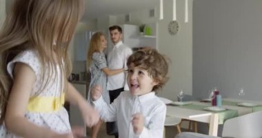 Yeni taşınma günü konseptinde mutlu genç bir aile, büyük modern ev koridorlarına koşan heyecanlı çocuklar, geçmişinde eşyaları olan aileler, ipotek kredisi, taşınma