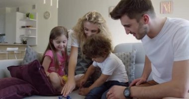 Mutlu aile oturma odasındaki kanepede oturuyor. Dört kişilik aile evlerinin oturma odasındaki kanepede birlikte oturuyorlar.