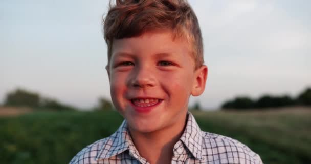 Портрет блондинки маленький хлопчик позує надворі і сміється . — стокове відео
