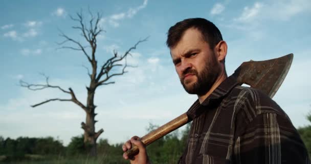 Lumberjack in the woods with an ax. Brutal bearded man with beard and moustache on summer day, sunny forest. Handsome man, hipster, lumberjack. Attractive bearded male outdoors in summer — Stock Video