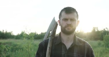 Omzunda balta olan çekici, sakallı bir adamın portresi.