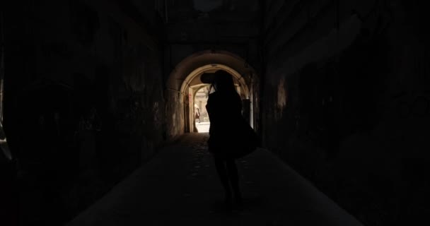 Свет в конце тоннеля. Силуэт женщины выходит из заброшенного тоннеля метро, направляясь к свету. — стоковое видео