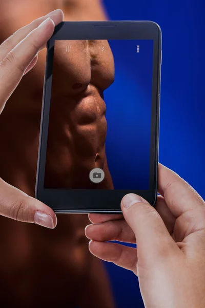 Photographing a muscular man abdomen — 图库照片