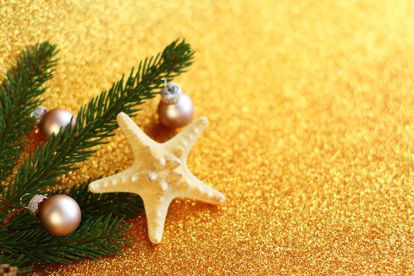 Tropikal Noel süslemesi, deniz yıldızı ve parlak altın arka planda kürk ağacı, tropik detaylarla dolu yeni yıl kutlama kartı. 