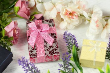 Sevgililer günü için romantik kompozisyon, düğün, doğum günü. Hediye kutuları, çiçekler, pembe kağıda sarılı kutu ve beyaz masa manzaralı gül lavantalı sakura çiçekleri.. 