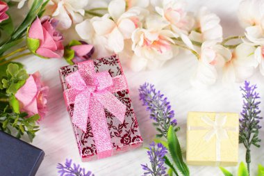 Sevgililer günü için romantik kompozisyon, düğün, doğum günü. Hediye kutuları, çiçekler, pembe kağıda sarılı kutu ve beyaz masa manzaralı gül lavantalı sakura çiçekleri.. 