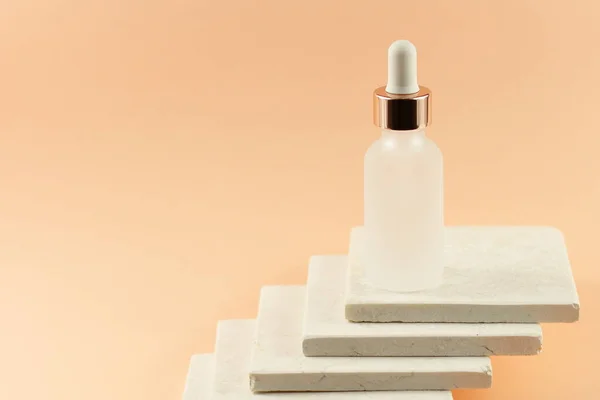 Doğal taş mermer zemin üzerinde pipeti olan şeffaf kozmetik şişeleri şeftali rengi dokusunda organik spa, kopyalama alanı 