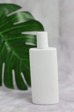 Palmiye yaprağı, güneş kremi, yağ, yüz bakımı ile mermer üzerinde beyaz plastik kozmetik şişe 