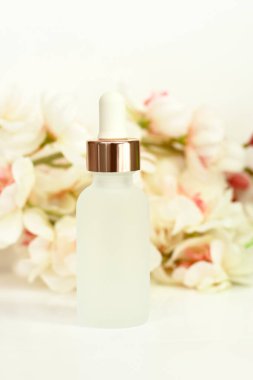 Beyaz çiçekli pipetli mat beyaz kozmetik şişesi ve ayna yansıması, cilt bakımı, kaplıca güzellik terapisi.