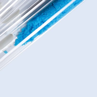 Test tüpünde mavi pullu kimyasallar, bakır (II) sülfat. Mavi arka planda kozmetik kimyasallar var. Kapat.