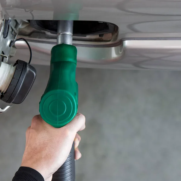 Gas station worker filling up bronze pickup truck tank (Top View). Closeup hand holding green gas pump nozzle.