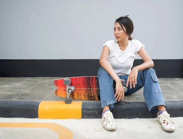 머리에 선글라스를 스케이트를 아시아 스케이트보드는 보행자 차선의 가장자리에 놓여져 — 스톡 사진