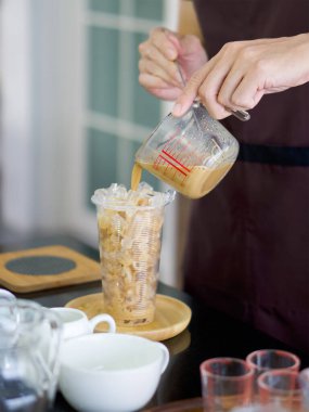 Profesyonel barista tezgahta kahve hazırlıyor. Plastik bardaktaki ölçü kabından elle kahve dökmek (Yakın çekim) ).