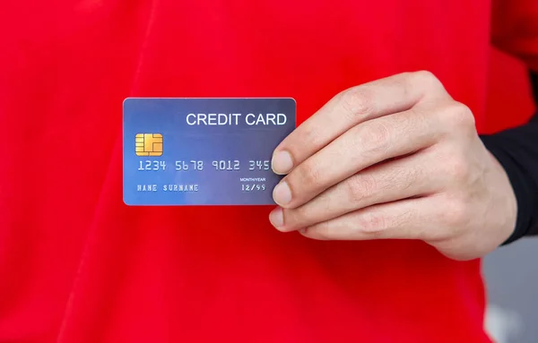 Blue credit card on the hand of an employee in a red uniform. Close up