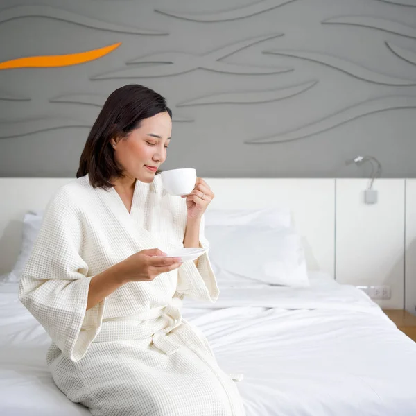 Asiatin Bademantel Trinkt Morgens Heißen Kaffee Auf Dem Bett — Stockfoto