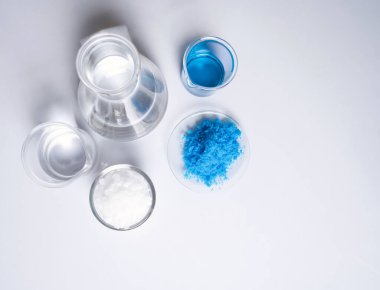 Beyaz laboratuvar masasında inorganik kimyasallar. Bakır (II) sülfat, mikro kristal balmumu, alkol. Kozmetik ve Tuvalet malzemeleri için kimyasal malzeme. Üst Görünüm