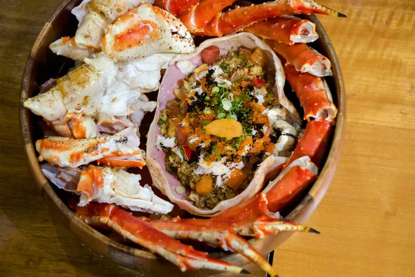 Live TARABA King Crab steamed on wooden tray. Legs and claws were cut into pieces. Taraba fried rice are in the crab shell consists of tobiko, Ikura roe, salmon and tuna sashimi. Japanese seafood.