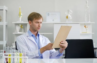 Genç Brezilyalı bilim adamı panoda kimyasal bileşik araştırmalarının sonuçlarını okudu. Kimya laboratuvarında çalışan bir atmosfer. Masadaki kimyasallarla dolu test tüpleri..